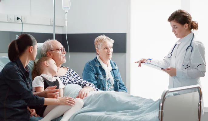 A doctor standing in front of a mature man with his relatives in a hospital and explaining something